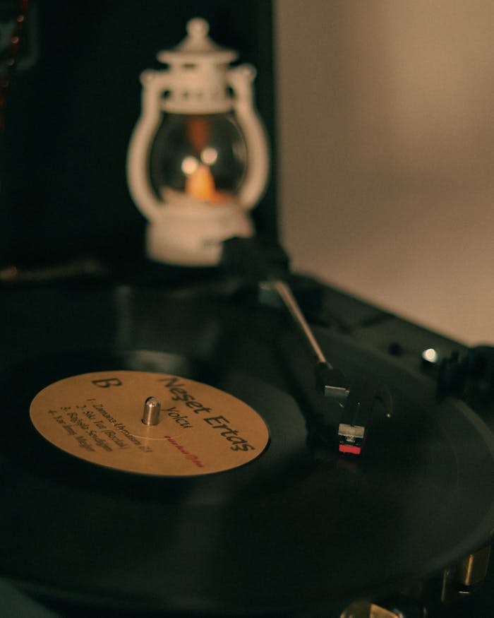 Vintage vinyl record player spinning a gramophone record with warm ambient lighting, creating a retro atmosphere.